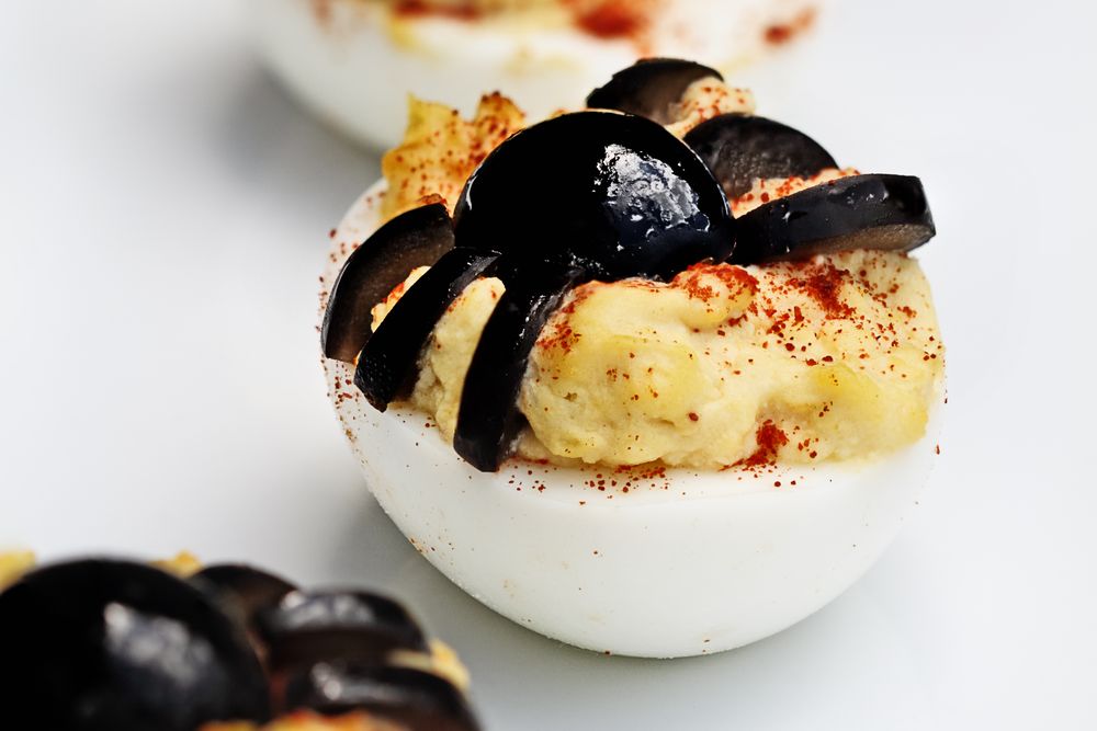 Huevos rellenos decorados como arañas con aceitunas negras y pimentón para Samaín